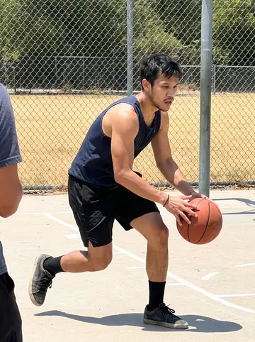 Cole, AI character: outdoor pickup basketball court at a park in East Austin, chain-link fence and dry grass beyond it
