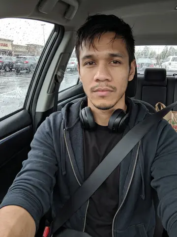 Cole, AI character: parked car outside a grocery store after buying dinner supplies, rain streaks on the side window