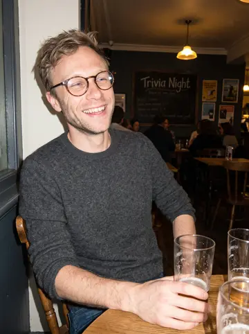 Jonah, AI character: a corner table at a Southeast Portland pub on trivia night, friends' half-empty pint glasses on the table