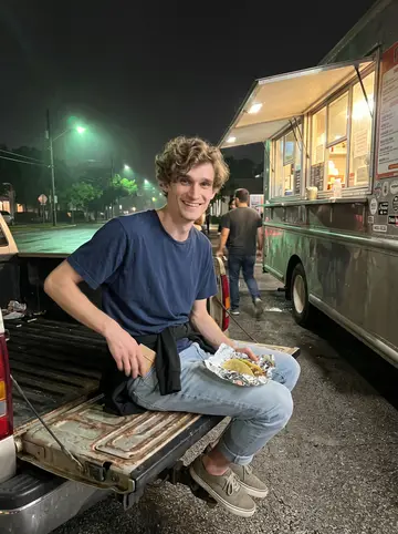 Beau, AI character: outside a late-night taco truck in Austin, sitting on the open tailgate of a friend's pickup with the…