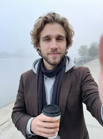 Camden, AI character: the river walk at dawn after a long night, Mississippi River fog behind him and a takeaway coffee just…