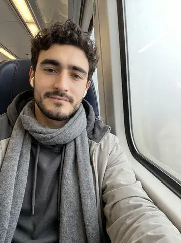 Ottavio, AI character: regional train seat on an early foggy morning between Bologna and a weekend visit south, window washed…