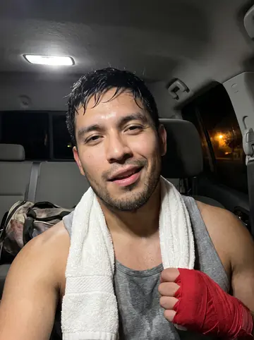 Santiago, AI character: an old boxing gym in Segundo Barrio on a Sunday morning, worn mats, a heavy bag, peeling paint, high windows