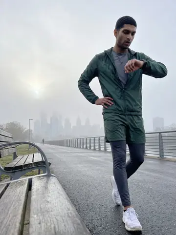 Noah, AI character: Schuylkill River Trail just after sunrise, damp path, river railing and hazy Center City buildings in the…