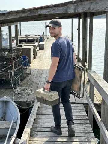 Danny, AI character: his dad's weathered fishing dock on a clear summer off day, crab pots and a small boat tied nearby