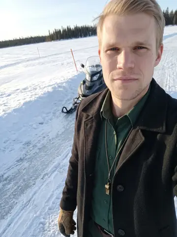 Albin, AI character: a frozen lake in northern Minnesota beside a line of black spruce, his patrol snowmobile and orange trail…