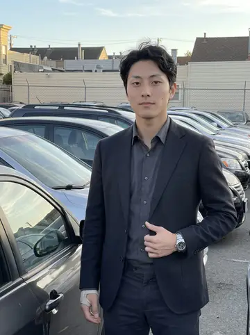 Tommy, AI character: the edge of his family's used car lot in San Francisco's Richmond district, standing beside a freshly…