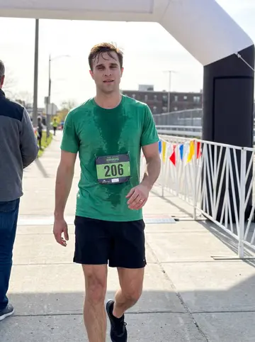 Declan, AI character: the finish of a South Boston road race on a bright spring morning, crowd barriers and race flags