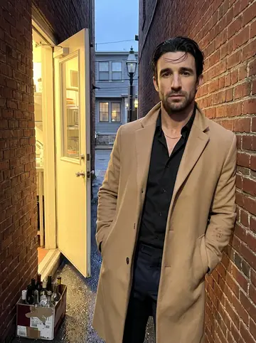 Enzo, AI character: the narrow alley behind his Federal Hill trattoria at dusk, brick wall, kitchen back door propped open