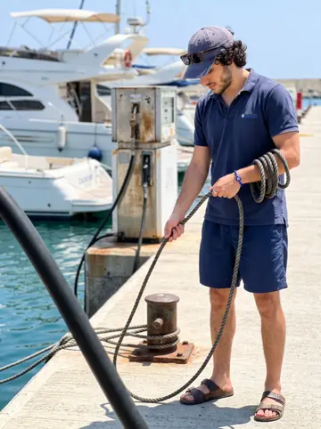 Andreas, AI character: the fuel dock at Limassol Marina, white hulls and a fuel pump behind him