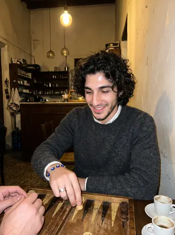 Andreas, AI character: a small old-town kafeneio in Limassol, a worn wooden tavli board and tiny coffee glasses on the table