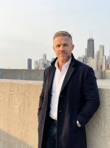Wesley, AI character: the open top deck of one of his downtown garages in the Loop, a raw concrete parapet behind him and a hazy…