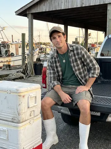 Grady, AI character: the shrimp docks near his family's old loading spot, sitting on the open tailgate of a work truck