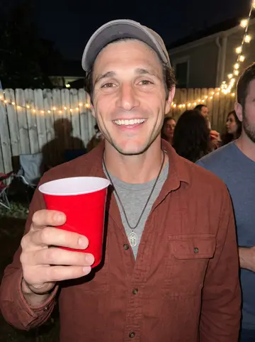 Grady, AI character: a crowded backyard holiday party in the Bywater, string lights and neighbors behind him