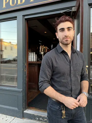 Conor, AI character: outside the family pub in South Boston just before opening, standing in the open doorway with the dark…