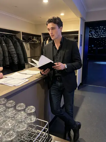 Kurt, AI character: inside the nightclub before the crowd arrives, near the coat check and a stack of clean glass racks