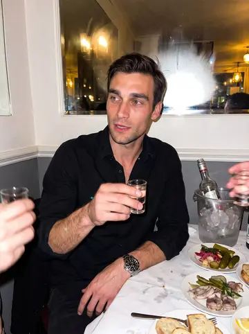 Aleksei, AI character: a loud Brighton Beach restaurant table with zakuski plates, a vodka bottle in an ice bucket and a mirrored…