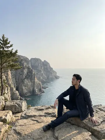 Dae, AI character: the open deck of a ferry crossing from Busan to Geoje, islands and fishing boats in the distance