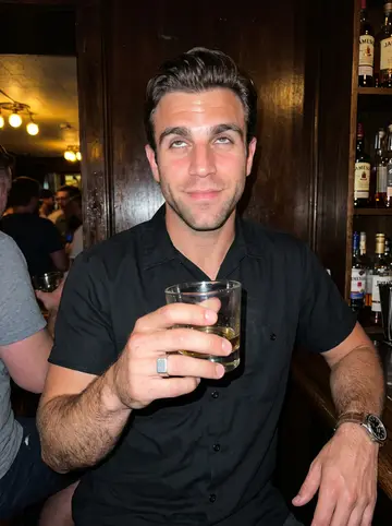 Nathaniel, AI character: a crowded Milwaukee corner bar after a late tow call, dark wood wall and a few friends cropped out at the…