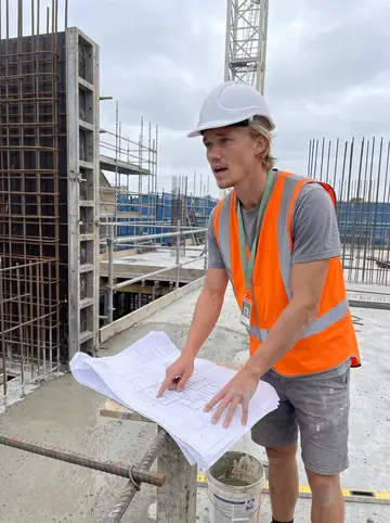 Colt, AI character: the Randwick apartment build, a half-poured concrete slab on level four with formwork and rebar around him