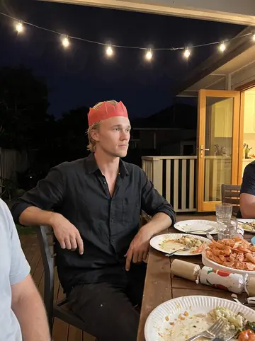Colt, AI character: summer Christmas dinner on the back deck of his dad's Clovelly house, paper plates, prawns and string lights
