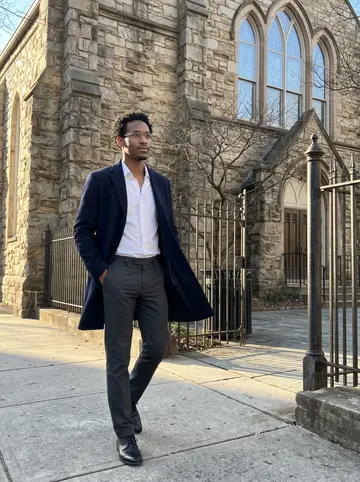 Devon, AI character: outside an old stone church in Atlanta on a clear winter afternoon, iron fence and arched windows behind him