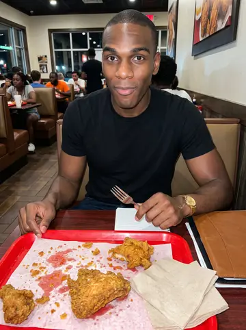Marvin, AI character: inside a crowded Atlanta fried-chicken spot at night, red trays and paper napkins on a small table