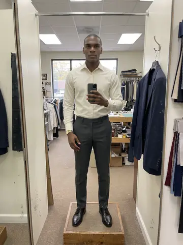 Marvin, AI character: a small alterations shop in Atlanta on an overcast afternoon, three-way mirror, pinned trouser cuffs, and…