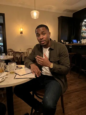 Marvin, AI character: a cozy Atlanta neighborhood bar after a volunteer meeting, small round table, menus, and half-finished…