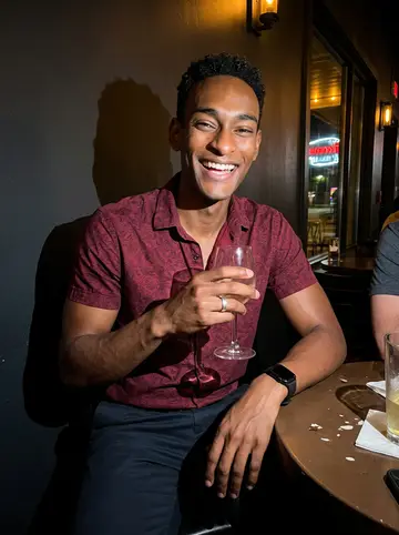 Papa, AI character: low-key Houston bar after the radio show, small table with friends just outside the frame and neon…