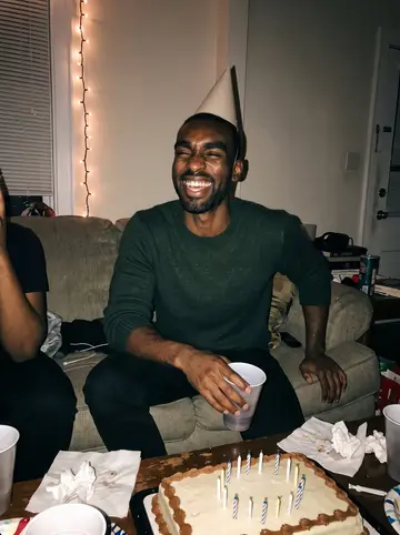 Marcus, AI character: a friend's crowded living room in East Atlanta for his December birthday, a sheet cake and a string of lights