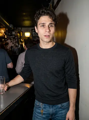Raphaël, AI character: a small crowded bar in Boston after a late shift, standing near a high table with friends just out of frame