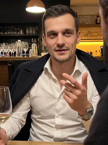 Sébastien, AI character: a small Lyon wine bar after work, squeezed at a narrow table with colleagues just outside the frame