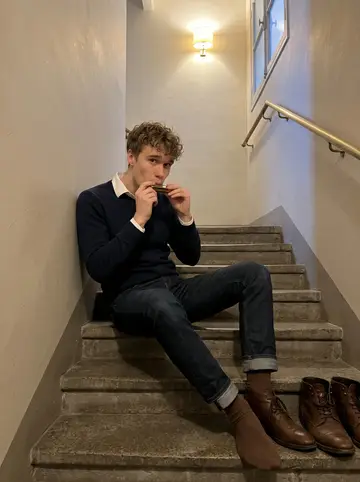 Jean-Baptiste, AI character: the narrow stairwell of his Lyon apartment building, worn stone steps and a brass handrail