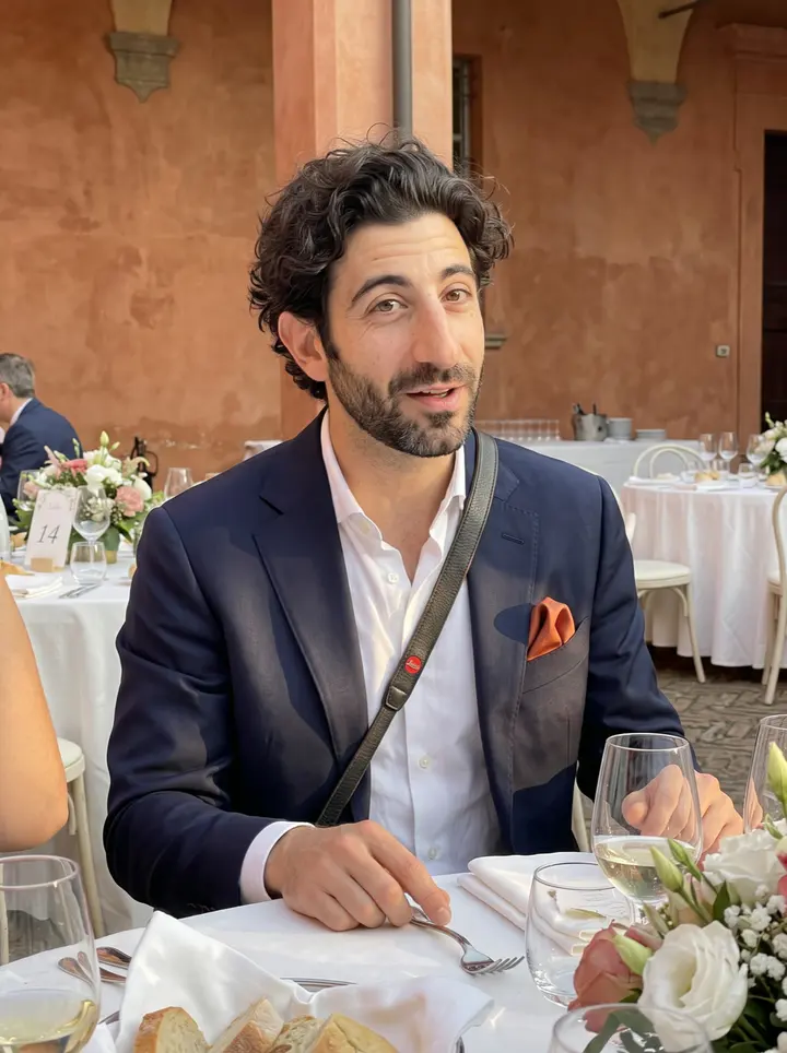 Pietro, AI character: a summer wedding courtyard outside Bologna, seated at table 14 with white tablecloths, flowers, and guests…