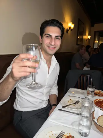 Ugo, AI character: back corner of a Providence Italian restaurant after a cousin's birthday dinner, red sauce plates and…