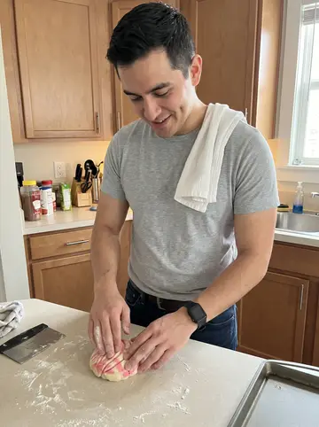 Ricardo, AI character: his apartment kitchen on a Sunday morning, baking tray of pink and white conchas on the counter