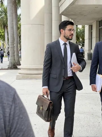 Hilario, AI character: outside the Miami federal courthouse after a maritime hearing, palm trees and pale stone columns in the…