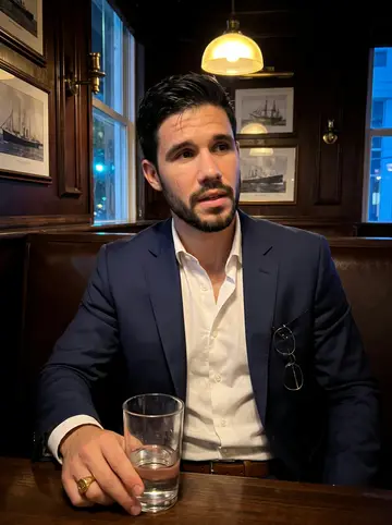 Hilario, AI character: a small dark-wood bar near Brickell after work, ship photos and brass fixtures on the wall behind him