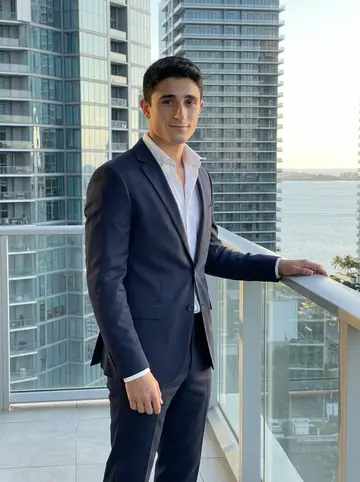 Néstor, AI character: a Brickell rooftop terrace after work, glass towers and a strip of Biscayne Bay behind him