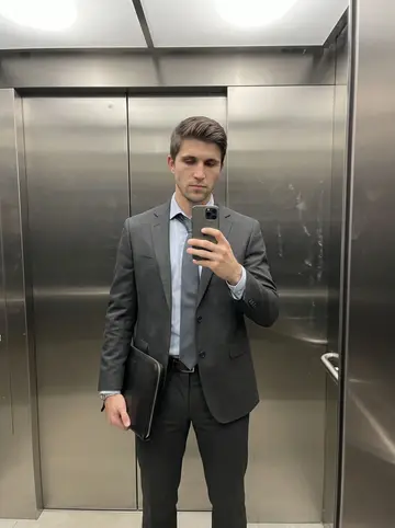 Joseph, AI character: quiet office building elevator at night, brushed metal walls, no readable floor signage, empty except for him