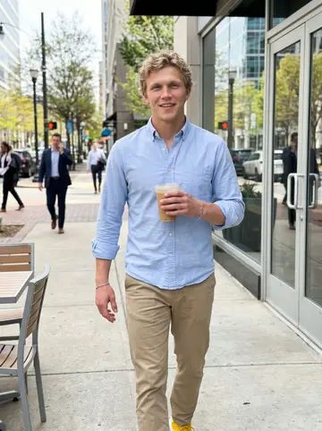Riley, AI character: a sunny sidewalk in Uptown Charlotte outside a coffee shop near the office, glass buildings and spring…
