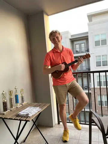 Riley, AI character: his apartment balcony in Charlotte at golden hour, thrift-store trophies lined up on a small outdoor…