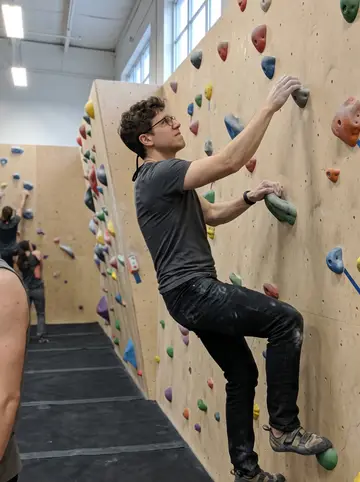 Zane, AI character: an indoor bouldering gym in Fremont on Sunday afternoon, colored holds on a matte climbing wall