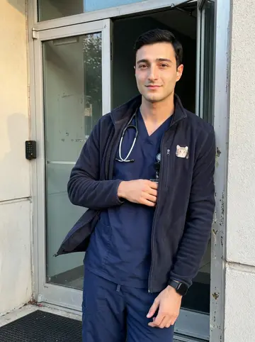 Greg, AI character: outside the staff entrance of a Philadelphia hospital near the ER, late afternoon between shifts