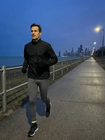 Drake, AI character: Chicago lakefront trail before sunrise with the dark lake and skyline behind him