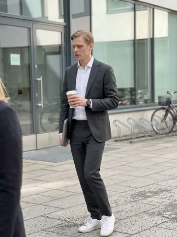 Niko, AI character: courtyard outside a Helsinki consulting office during a short work break, glass doors and bicycle racks in…