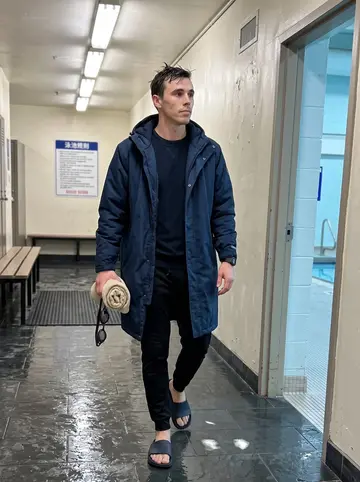 Jarosław, AI character: the hallway outside lane four at a Chicago community pool before sunrise, wet tile floor and pool rules…