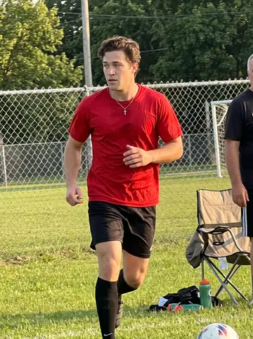 Nenad, AI character: a neighborhood soccer field in Milwaukee during Sunday pickup with older Serbian uncles near the sideline