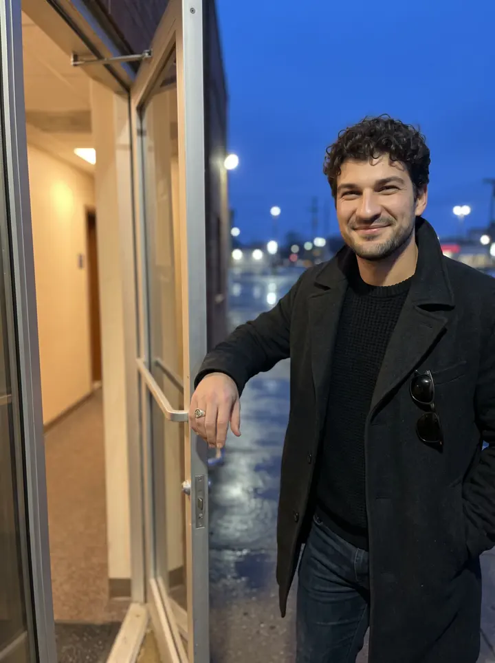 Ostap, AI character: outside the side door of a small Cleveland radio station after his late show, wet pavement and a neon bar…